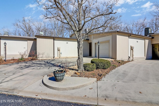 view of side of home featuring central AC unit, driveway, and a garage