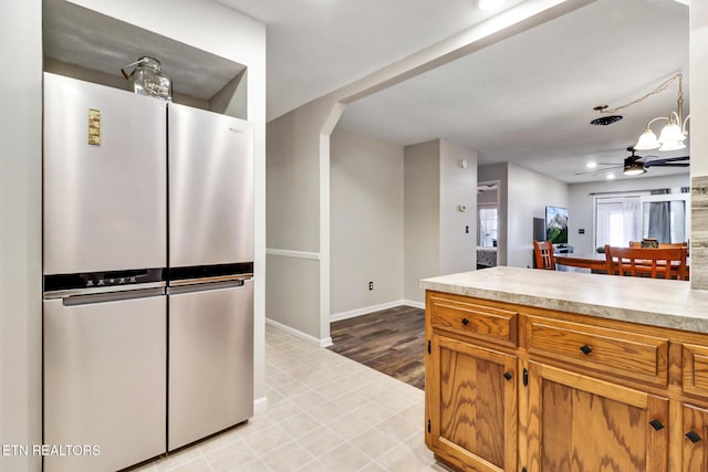 kitchen with ceiling fan, baseboards, light countertops, freestanding refrigerator, and brown cabinetry