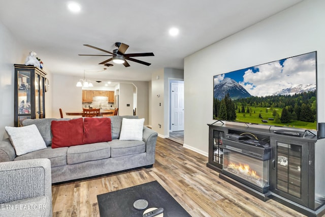 living area with baseboards, recessed lighting, arched walkways, ceiling fan, and light wood-style floors