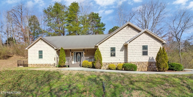 ranch-style home featuring metal roof and a front lawn