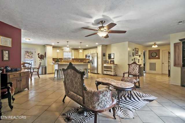 living area with light tile patterned floors, ceiling fan, visible vents, and a textured ceiling