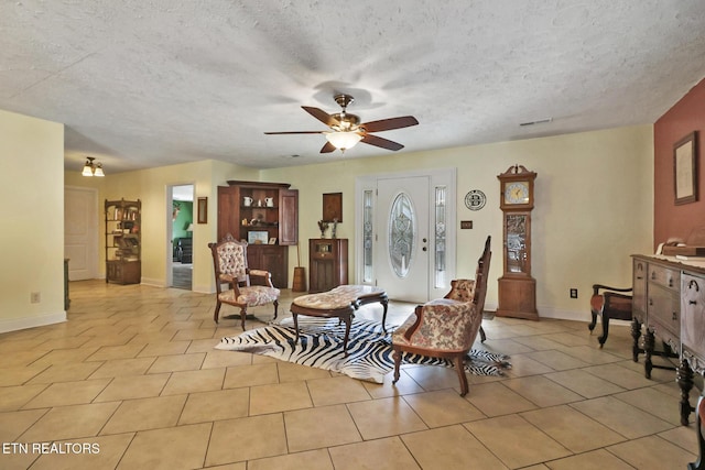 interior space featuring light tile patterned floors, visible vents, ceiling fan, a textured ceiling, and baseboards