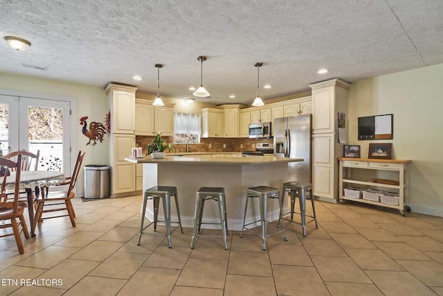 kitchen featuring a breakfast bar area, light tile patterned flooring, appliances with stainless steel finishes, decorative backsplash, and a center island