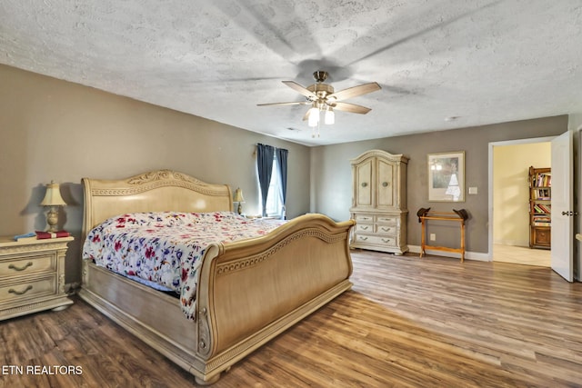 bedroom featuring a textured ceiling, wood finished floors, a ceiling fan, and baseboards