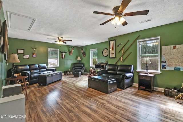 living room with baseboards, a textured ceiling, visible vents, and wood finished floors