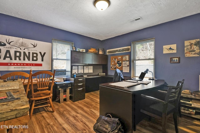 office with a textured ceiling, visible vents, and wood finished floors