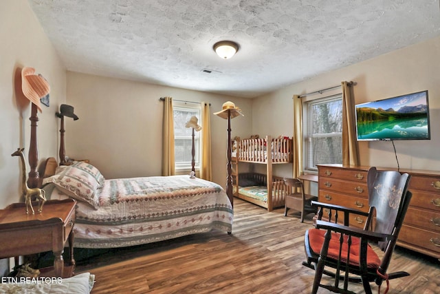 bedroom with a textured ceiling, wood finished floors, and visible vents