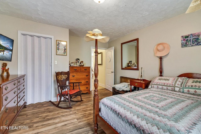 bedroom with a textured ceiling and wood finished floors