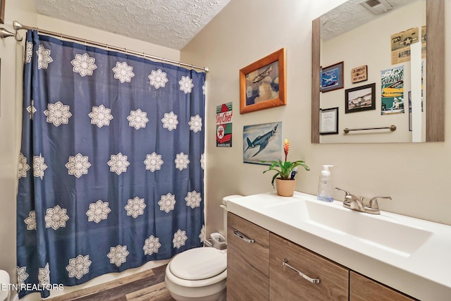 full bathroom with visible vents, toilet, a shower with curtain, a textured ceiling, and vanity