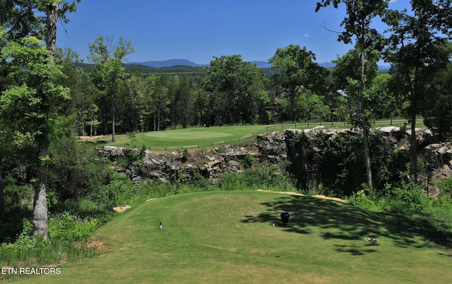 surrounding community with a yard, view of golf course, and a view of trees