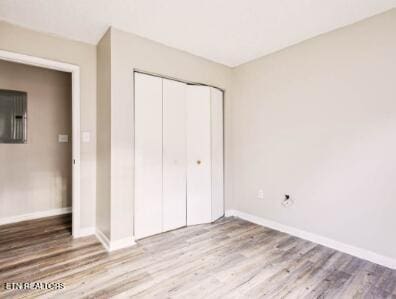 unfurnished bedroom featuring a closet, baseboards, and wood finished floors