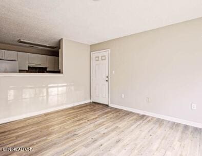 empty room featuring wood finished floors, baseboards, and a textured ceiling