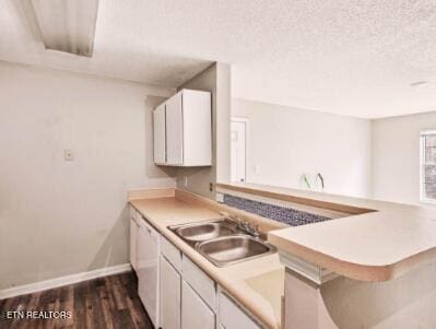 kitchen with baseboards, dark wood finished floors, white cabinets, a textured ceiling, and a sink