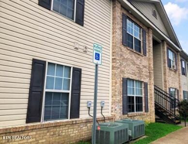 view of side of home featuring cooling unit and brick siding