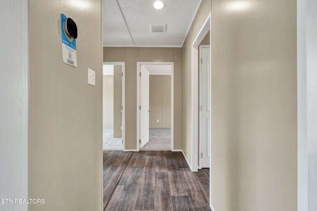 hallway with visible vents, dark wood-type flooring, and a textured ceiling
