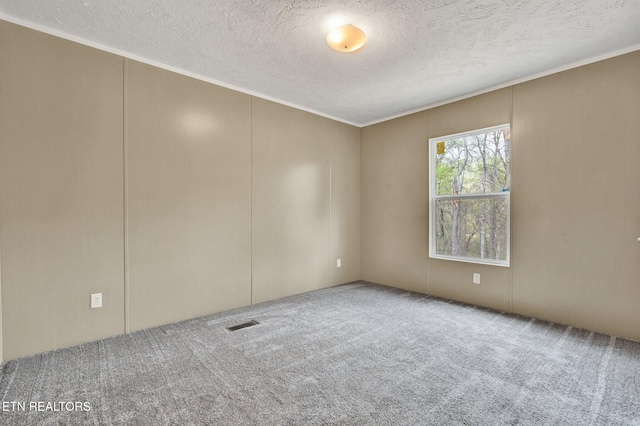 carpeted spare room featuring a textured ceiling and visible vents