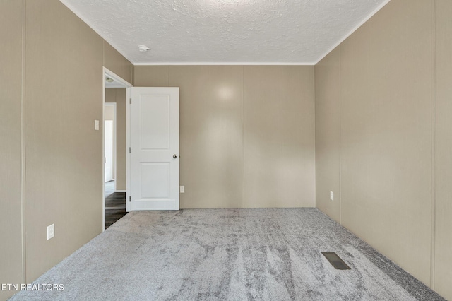 spare room with a textured ceiling, visible vents, carpet, and ornamental molding