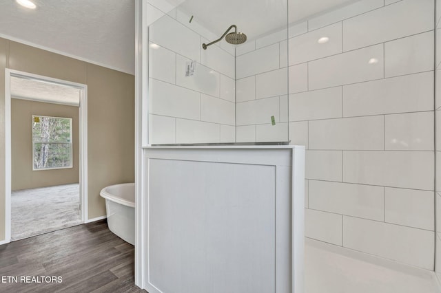 bathroom with a textured ceiling, a tile shower, a freestanding tub, and wood finished floors