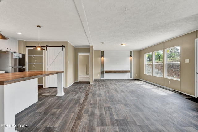 unfurnished living room with a textured ceiling, a barn door, and dark wood-style flooring