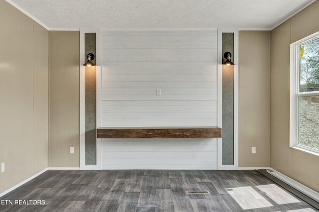 unfurnished room with a textured ceiling, visible vents, and dark wood-style flooring