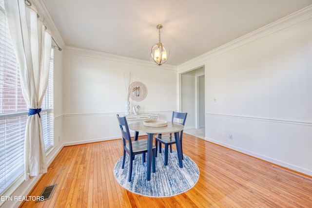 dining area with visible vents, crown molding, an inviting chandelier, and hardwood / wood-style flooring