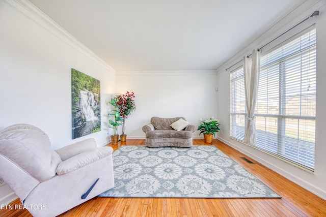 living area featuring ornamental molding, visible vents, and hardwood / wood-style flooring