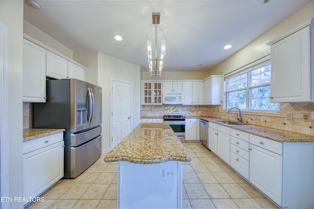 kitchen with a sink, stainless steel appliances, a kitchen island, and white cabinetry