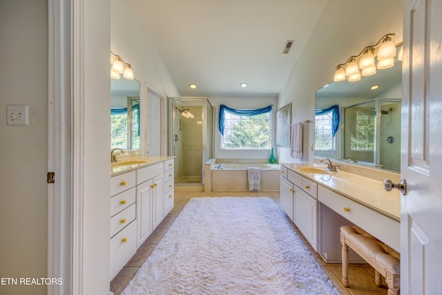 bathroom featuring two vanities, a stall shower, tile patterned flooring, and a sink