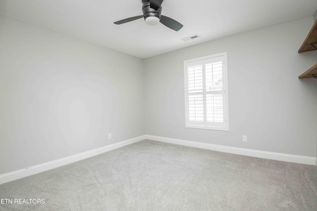 empty room with carpet floors, a ceiling fan, visible vents, and baseboards