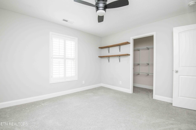 unfurnished bedroom featuring carpet floors, visible vents, baseboards, a closet, and a walk in closet