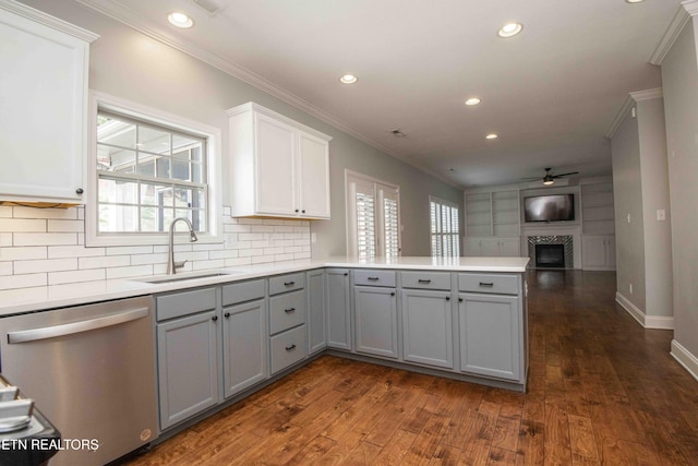 kitchen featuring a sink, a peninsula, gray cabinets, and stainless steel dishwasher