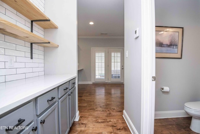 interior space with tasteful backsplash, dark wood-type flooring, crown molding, gray cabinetry, and open shelves