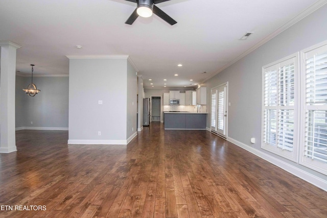 unfurnished living room featuring dark wood-type flooring, crown molding, baseboards, and ceiling fan with notable chandelier