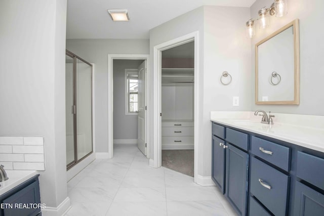 full bath featuring vanity, baseboards, marble finish floor, a shower stall, and a walk in closet