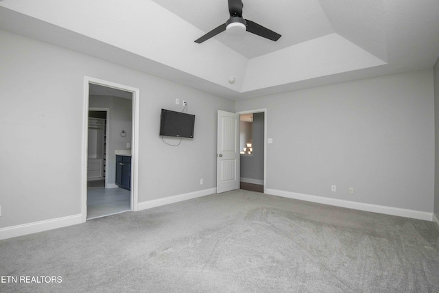 unfurnished bedroom featuring carpet floors, a raised ceiling, and baseboards