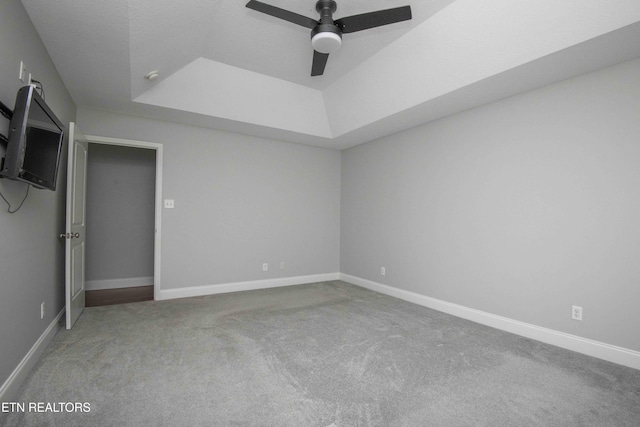 unfurnished bedroom featuring a tray ceiling, carpet flooring, a ceiling fan, and baseboards