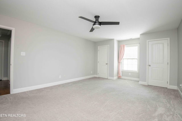 interior space with carpet, baseboards, ceiling fan, and attic access