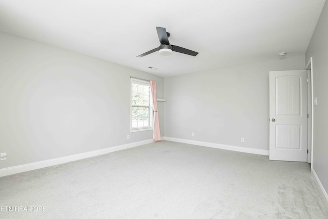 carpeted spare room featuring a ceiling fan and baseboards