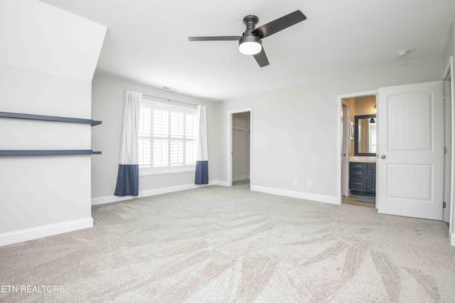 unfurnished bedroom with baseboards, ensuite bathroom, a spacious closet, carpet floors, and a closet