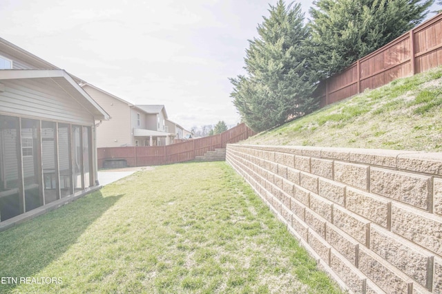 view of yard featuring a sunroom and a fenced backyard