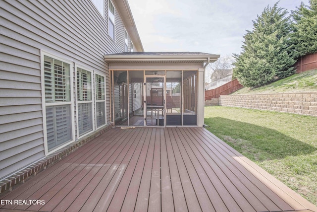 deck featuring a sunroom, fence, and a yard