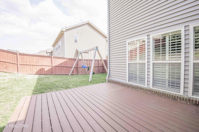 wooden terrace with a lawn, a playground, and a fenced backyard