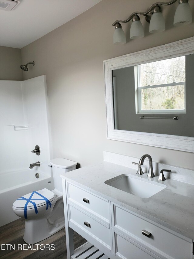 full bath featuring visible vents, toilet, shower / tub combination, wood finished floors, and vanity