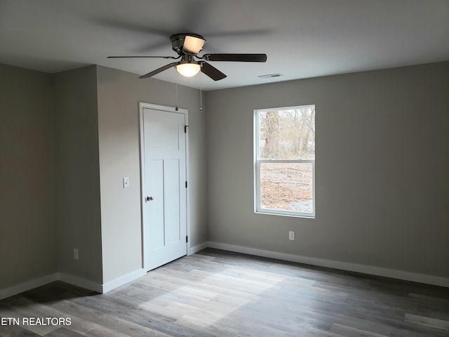 unfurnished bedroom with a ceiling fan, visible vents, baseboards, and wood finished floors