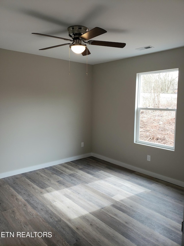 spare room featuring visible vents, baseboards, and wood finished floors