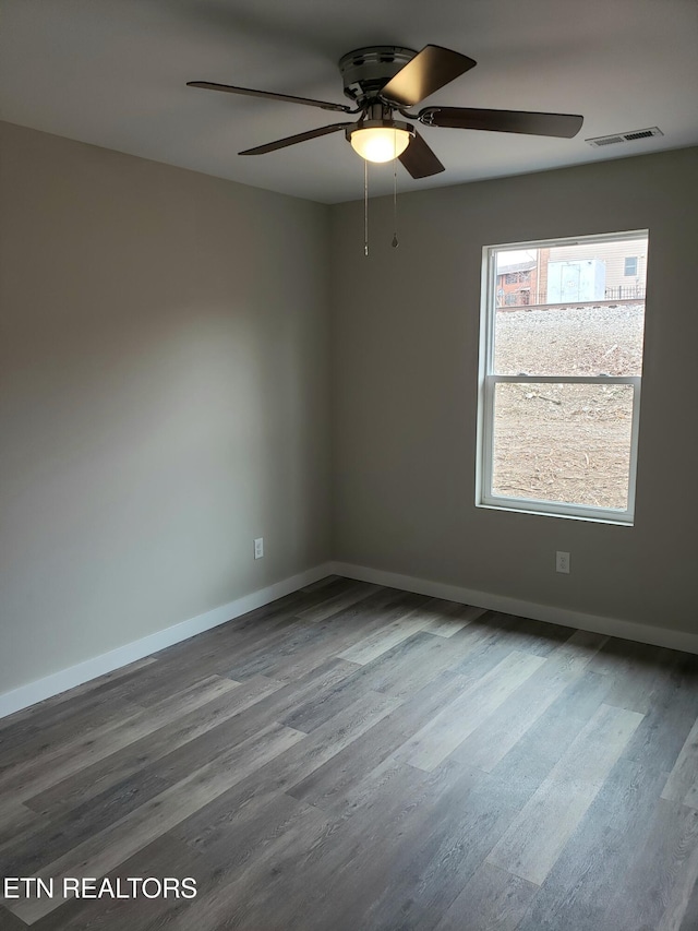 empty room featuring ceiling fan, wood finished floors, visible vents, and baseboards