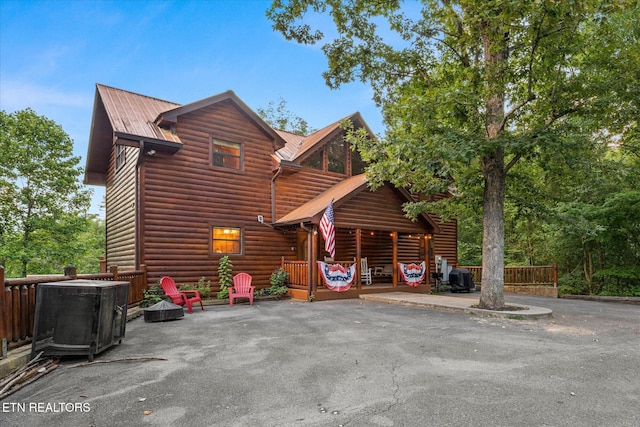 back of property featuring metal roof, log veneer siding, and a patio