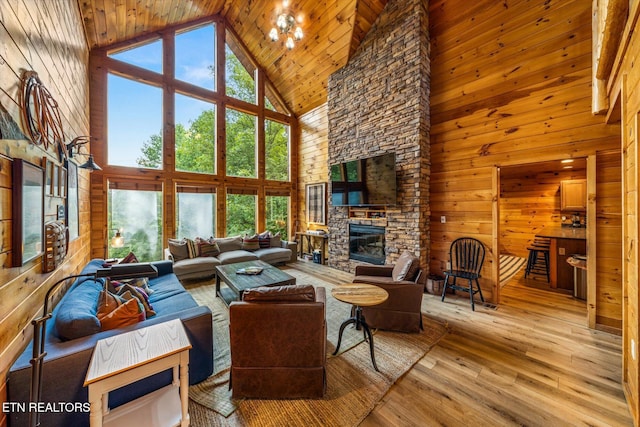 living room with a wealth of natural light, wood walls, a stone fireplace, and hardwood / wood-style flooring