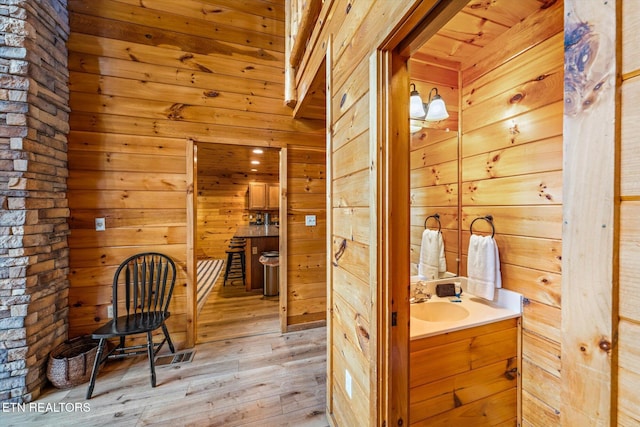 bathroom featuring wooden walls, vanity, and wood finished floors