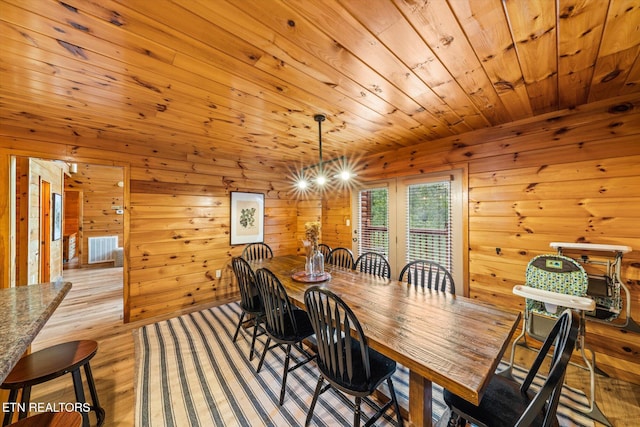 dining room with wooden ceiling, light wood finished floors, visible vents, and wood walls